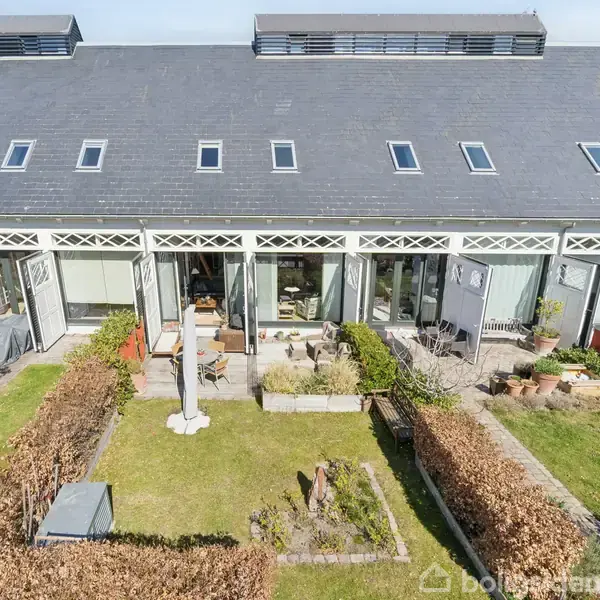 Rækkehus med store vinduer åbner ud til en velplejet have med buske og terrasser. Taget har flere ovenlysvinduer. Området er beboelsesområde med velholdte jordstykker.