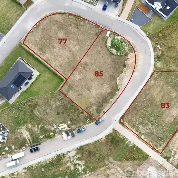 Udplotning af tre byggegrunde markeret med numrene 77, 85 og 83. Grundene ligger ved en vej i et boligområde, hvoraf én allerede har et hus og biler parkeret foran.