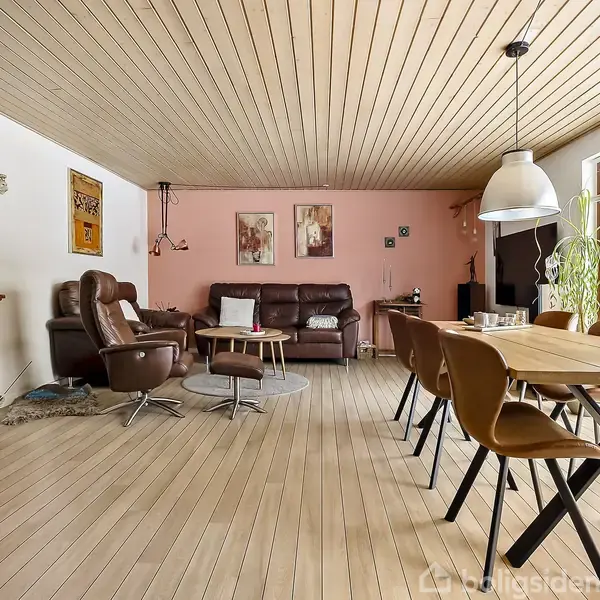 Stue med træloft har lædersofa og lænestole (objekt), arrangeret i samtalegruppe (handling). Ved siden af spisebord med stole og stor lampe i et lyst rum (kontekst).