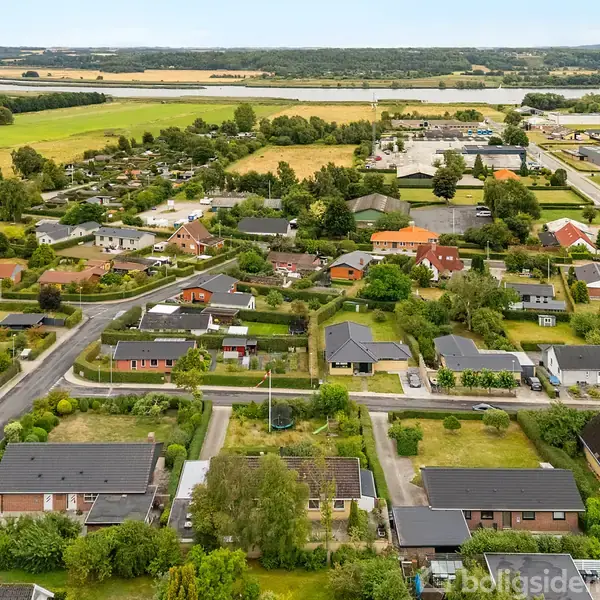 En bebyggelse med huse ligger fredeligt i et grønt, landsbylignende område. Huse med haver er omgivet af veje og marker i en landlig oplandskontekst.