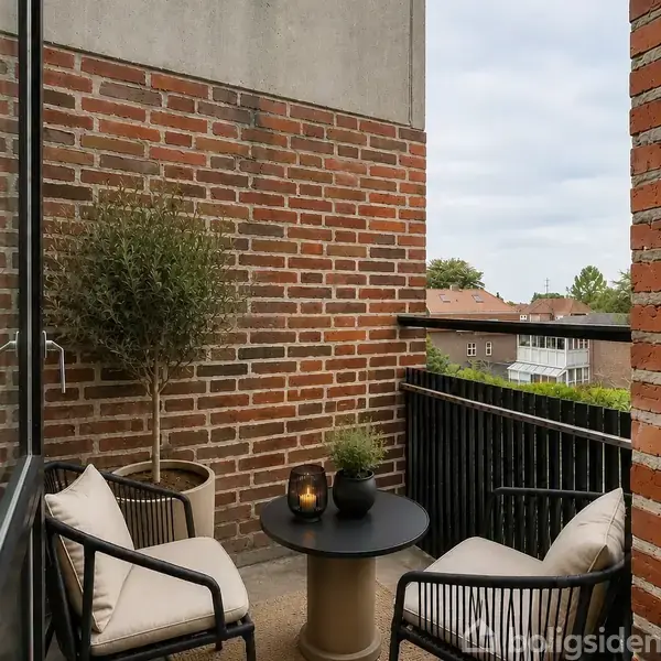 Et lyst rum med trægulv, et hvidt indbygget skab og ovn. Store vinduer giver udsigt til røde murstensbygninger udenfor. En glasdør fører til en balkon.