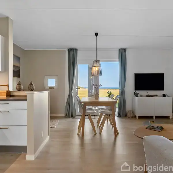 Et moderne køkken har hvide skabe, en minimalistisk vask og en opvaskemaskine. Der er en flisebagvæg, nogle dekorative genstande og billeder på væggene, hvilket skaber en stilfuld atmosfære.