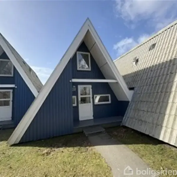 Blåt A-formet hus står stille på en grøn græsplæne under en klar blå himmel. Huset har en hvid dør og små vinduer på for- og tagsiden.