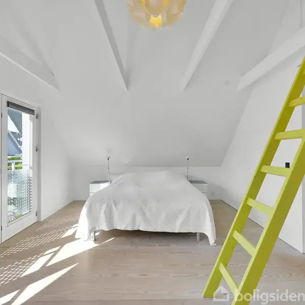 Seng står stille i et hvidt rum med højt til loftet, trænger til et lyst, minimalistisk udtryk. En gul stige læner sig op ad væggen nær to store døre ud til en altan.