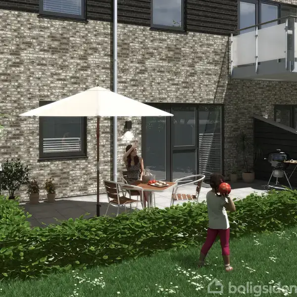 Terrasse med bord og stole under parasol. En person serverer mad. Foran er en grøn græsplæne med en person, der leger med en bold. Murstensbygning i baggrunden.