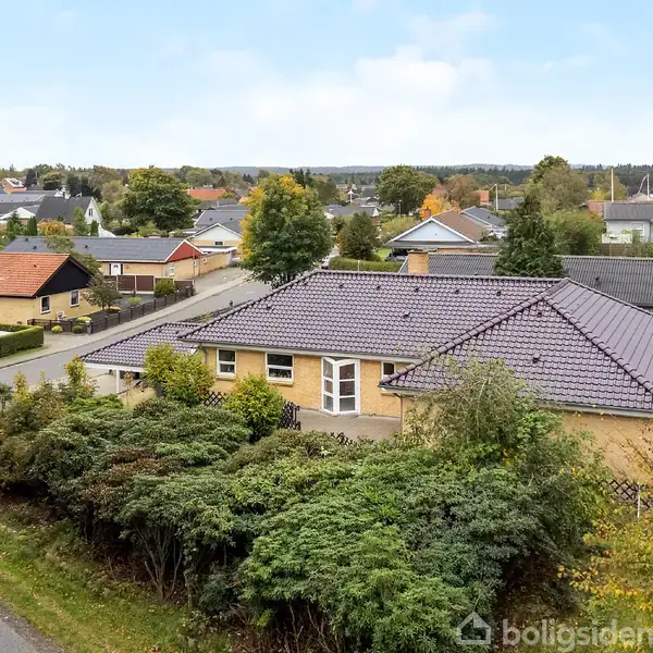 Huset ligger i et roligt boligkvarter med en have omgivet af buske. Nabolaget består af andre villaer og træer, der strækker sig over en let kuperet bakke.