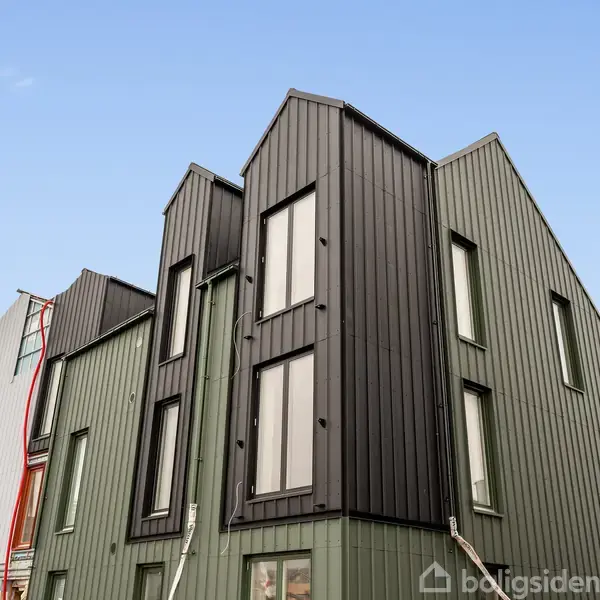 Moderne byhuse står tavlelignende uden handling mod en klar, blå himmel i et byområdemiljø.