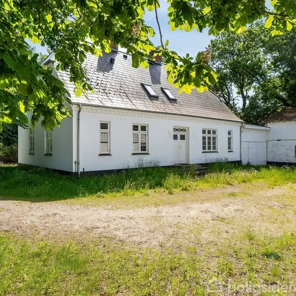 En trætrappe med hvidmalet gelænder fører opad i et moderne rum med mørkegrå flisegulve. Til venstre ses en åben dør ind til et lyst værelse.