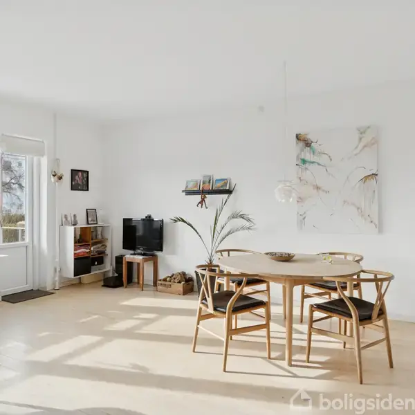 Et spisebord med stole står i en lys stue med hvidmalede vægge. Rummet har store vinduer, en reol med dekorative genstande, og et kunstværk på væggen.
