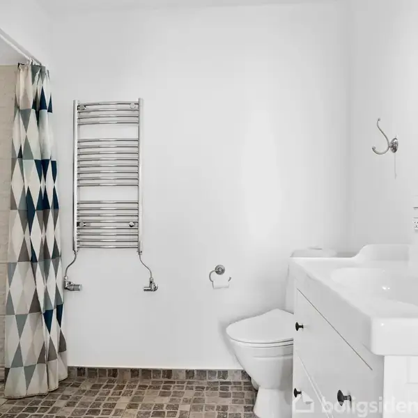 Et lyst rum med trægulv har to store vinduer med persienner, som lukker naturligt lys ind. Loftet er dekoreret med hængende grønne planter. 주변은 enkel og hvidmalet.