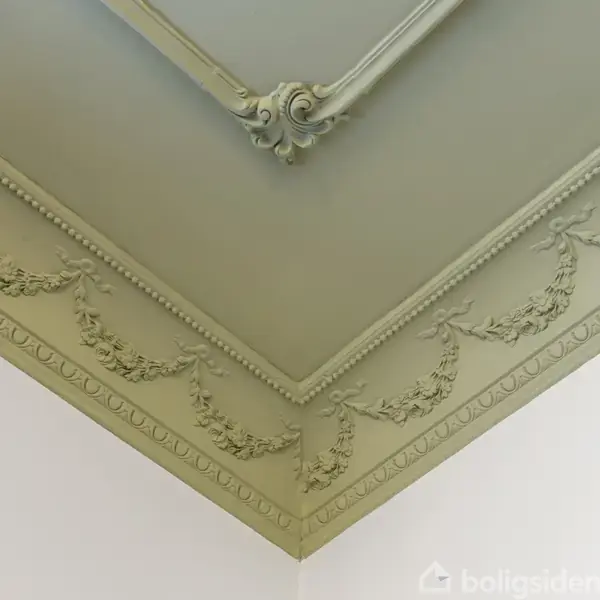 Dekorativt loft med ornamenter i en firkantet hjørneopstilling; grønne guirlander og perlekant pryder kanten, mens loftet ligger i glat, lysgrøn nuance.