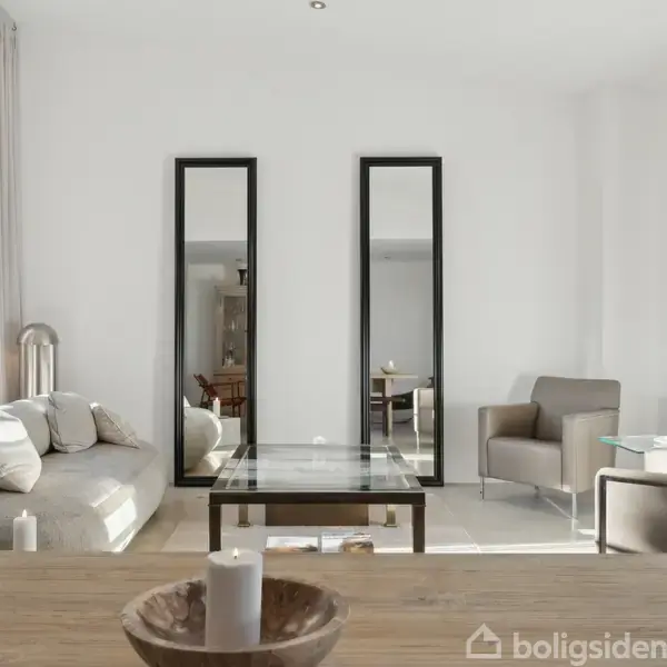 Stue med en grå sofa og to lænestole centreret omkring et glasbord, omgivet af store vinduer og tre høje spejle langs en hvid væg, der skaber en lys atmosfære.