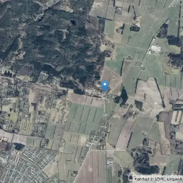 Kortnål markerer en placering midt i et landdistrikt med marker, skove og små landsbyer synlige omkring. Området er opdelt i forskellige felter og veje, der forbinder bygninger og landskaber.