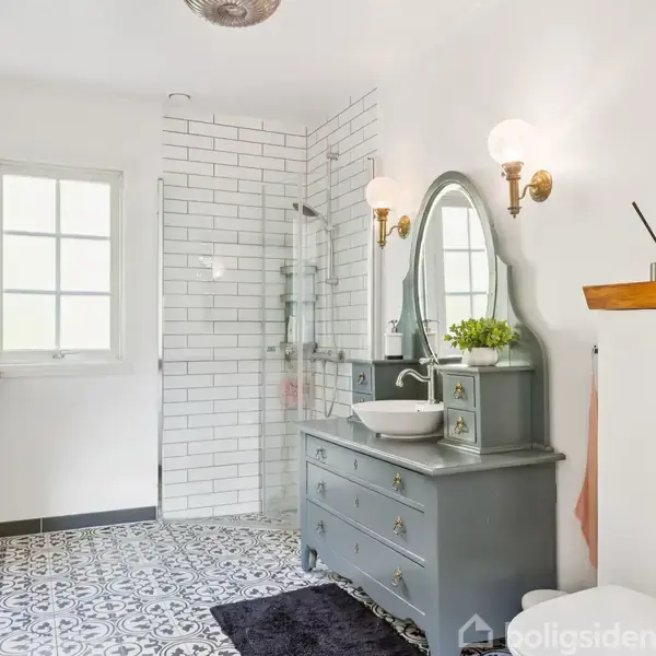 Et badeværelse med en grå kommode, der som vaskebord har en hvid vask og spejl. Fliser har sort-hvidt mønster. Brusedør er af glas. Tekst: "today is a good day for a good day".