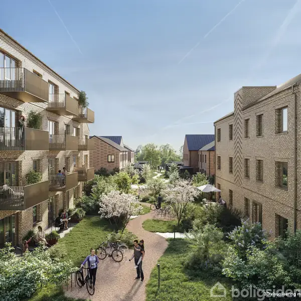 Flere boligbygninger i mursten omkranser en frodig gårdhave. Personer med cykler nyder det grønne område. Stier og blomstrende træer tilføjer en fredelig atmosfære mellem bygningerne.