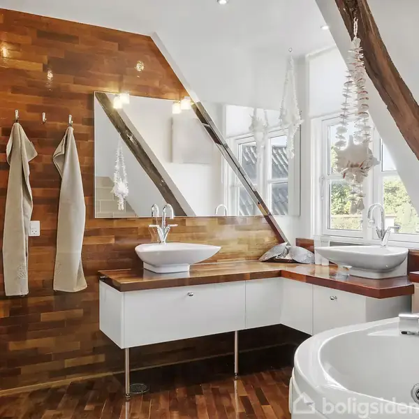 Stor terrasse med sort spisebord og seks stole, stillet under en åben pergola. I baggrunden ses en grøn have med træer, græsplæne og en træ-gynge.