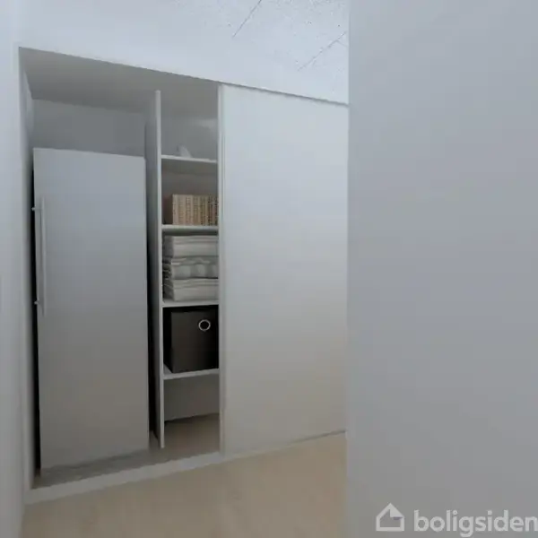 Et hvidt indbygget skab står i et lyst rum. Den ene skydedør er åben, og afslører hylder med bøger, bokse og mapper indeni.