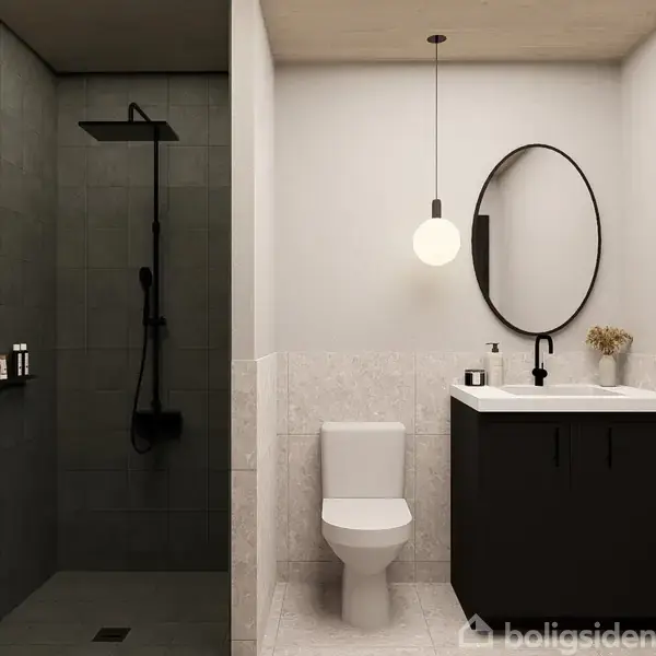 Toilet står foran en mørk træ-vask med en rund spejl over. En pendellampe hænger over vasken. Bruseområde til venstre med fliser og hylde med flasker.