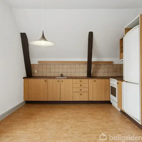 Køkken med træskabe står tomt. En vask er indbygget i bordpladen. En ovn er til højre, ved siden af et stort køleskab. En lampe hænger over gulvet.