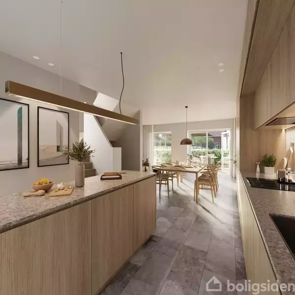 Køkken-alrum med lys trækøkken, grønne planter og frugter på bordpladen. I baggrunden ses en spisestue med spisebord, stole og glasdøre, der fører til en terrasse.