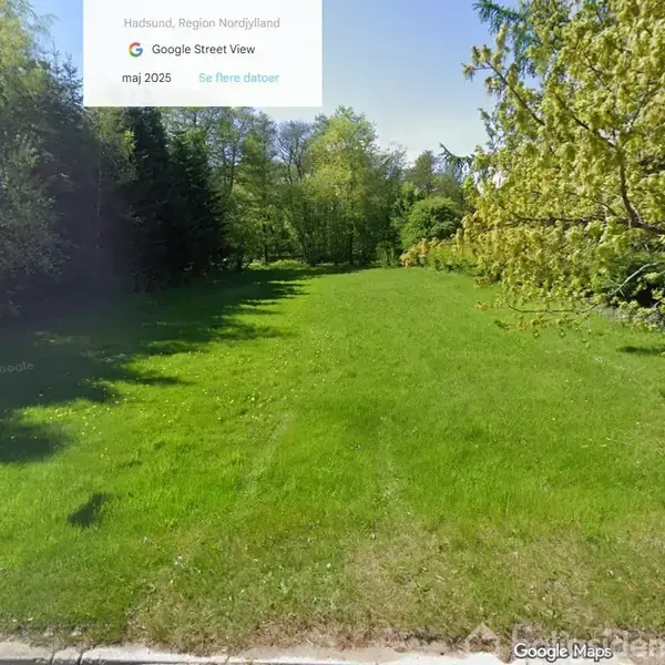 En grøn græsplæne strækker sig gennem en park omgivet af træer. Øverst står teksten: "Hadsund, Region Nordjylland, Google Street View, maj 2025, Se flere datoer."