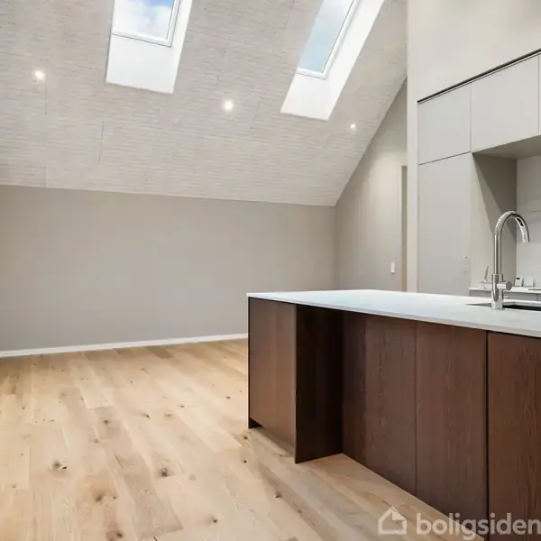 Køkken med brun køkkenø og hvid bordplade. Ovenlys gør rummet lyst, trægulv strækker sig til væg med vinduer. Minimalistisk design med indbyggede loftslamper.