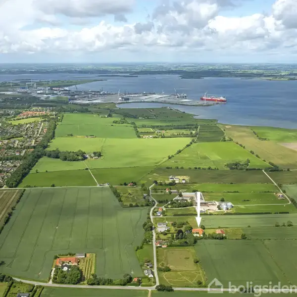 Landskab strækker sig med marker og gårde, mens en stor flod løber i baggrunden. En stor skib er synligt på vandet ved horisonten. Skydække er spredt over himlen.