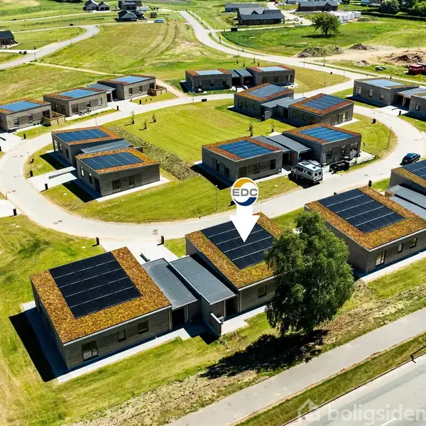 Et cirkulært boligområde med flere ens huse udstyret med solpaneler på tagene. Huse omkranser en grøn fælles plads i et åbent og grønt landskab. EDC-logo indikerer ejendomsmægler.
