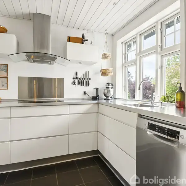 Dør med glas indsats står ved siden af knagerække med jakker i en gang. Sorte fliser dækker gulvet. Væggen har indrammet kunst og skilt med teksten "Home Office, Sweet Home Office."