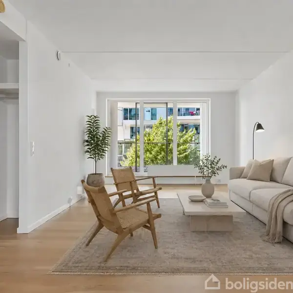 En lys stue med en beige sofa, to træstole og et sofabord på et tæppe. Store vinduer lukker naturligt lys ind, og der er en gulvlampe ved sofaen.