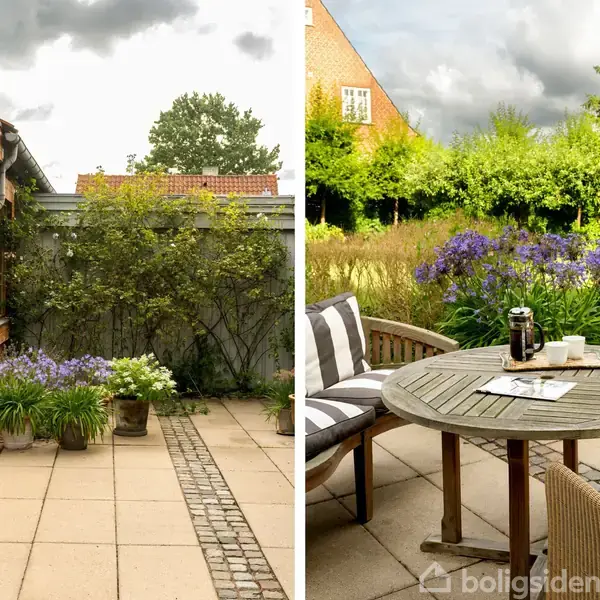 En terrasse med fliser og blomsterkrukker ved siden af et hus med trævægge. Et rundt bord med stole, tepotte og aviser står omgivet af frodig have og blomster.