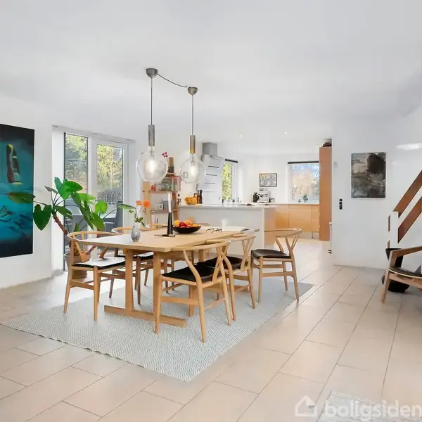 En moderne bil holder parkeret foran en gulstensvilla med fladt tag. I forgrunden ses en dobbelgarage, og haven er anlagt med små træer og buske.