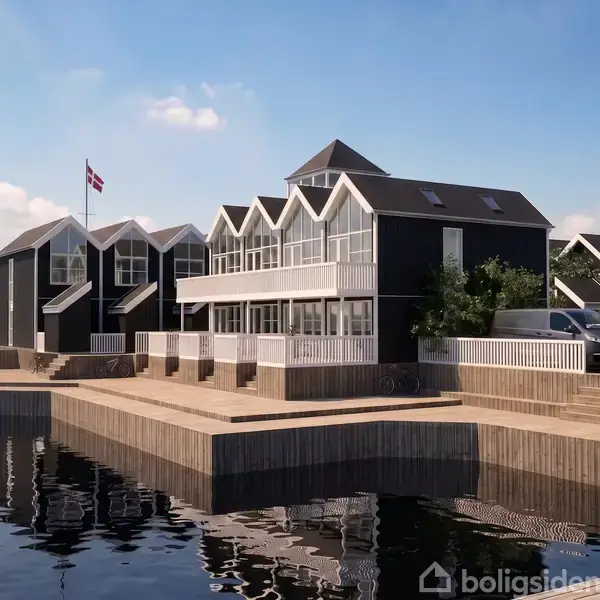 Moderne rækkehuse står ved en kaj, afspejlet i vandet. Husene har sorte facader med hvide detaljer. Flaggregninger pryder området, og biler er parkeret ved siden.