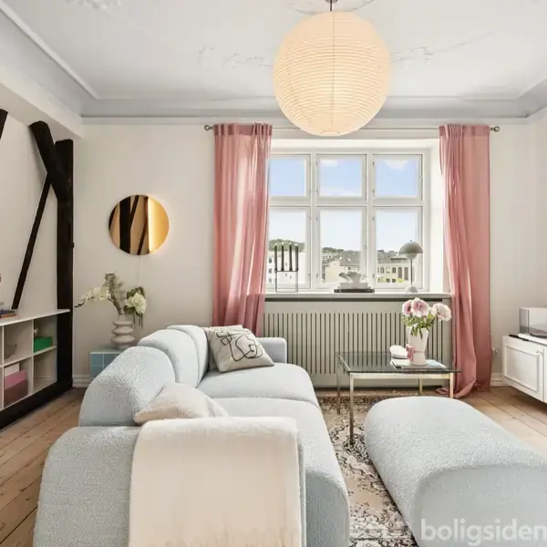 Stue med lyseblå sofa og sofabord i midten, pladevæg med hylder til venstre. Rosa gardiner hænger ved vinduet. Fladskærms-TV på væggen til højre.