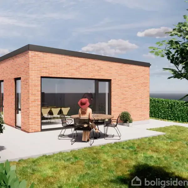 En kvinde sidder ved et rundt bord udenfor en moderne bygning med røde mursten og store vinduer omgivet af en velplejet have med grønne buske og et hegn.