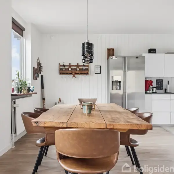 Et moderne, to-etagers hus med store vinduer står omgivet af stålhegn og en lille have. Husets facade er mørkegrå, og det er placeret mellem andre boliger i et beboelseskvarter.