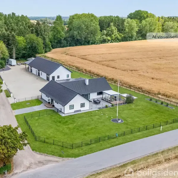 En hvid bygning med sort tag står på en velplejet græsplæne ved siden af en stor gårdsplads. Omkringliggende skov og mark omkranser ejendommen. Øverst står teksten "AI visualisering".
