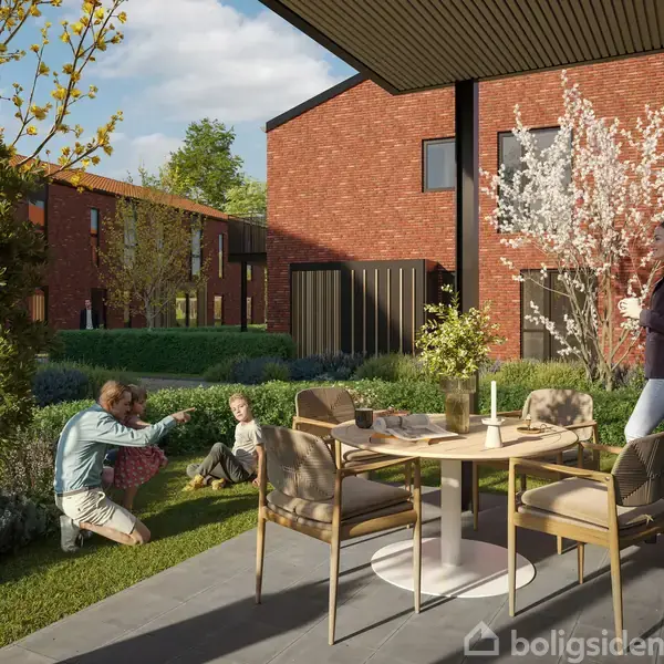 En person står ved et rundt bord med stole i en have. To personer leger med et barn på græsset. Røde murstensbygninger omkranser haven med blomstrende træer.