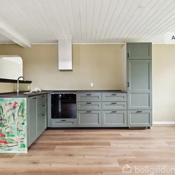 Et moderne køkken med grønne skabe og skuffer står i et rum med trægulv og lyse vægge. En væg har et naturmural. Tekst: "AI visualisering".