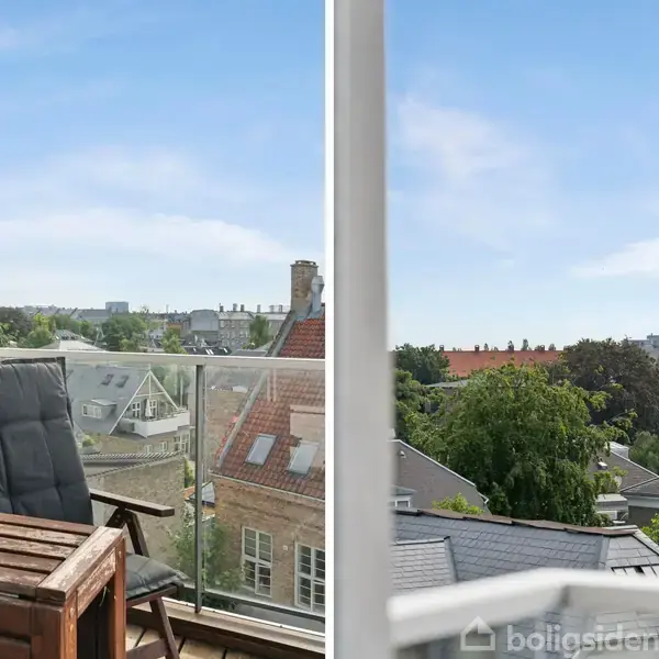 En altan med en træstol og bord med en plante, overfor en blå himmel over hustage og træer.