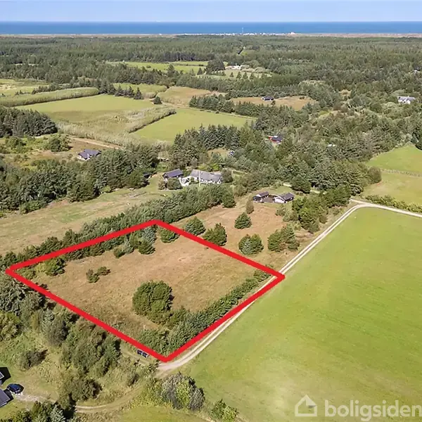 En mark med markeret område. En rød linje omkranser et stykke land, omgivet af grønne marker, skov og spredte beboelseshuse i et landligt landskab.