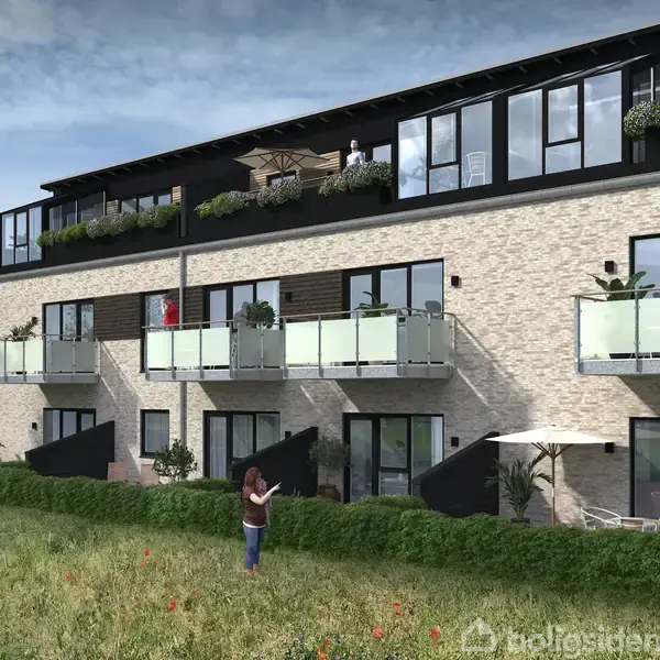 En række moderne lejligheder med glasbalkoner. Folk står på altanerne og i græsset foran bygningen under en overskyet himmel.