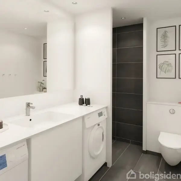 Et moderne badeværelse med vaskemaskine og håndvask på en hvid bordplade. Til højre er et toilet og planterammer på væggen. Mørke klinker dækker gulvet og omkring bruseområdet.