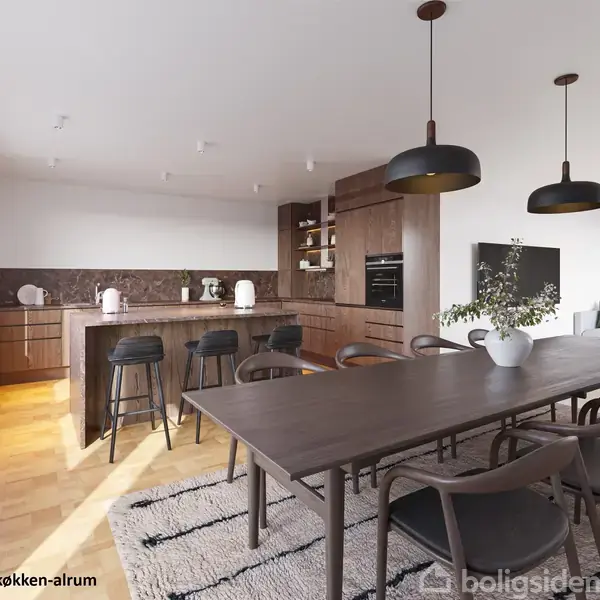 Et moderne køkken-alrum med mørkt træmøblement; et stort spisebord omkranset af stole. I baggrunden ses et køkkenområde med barstole. Store vinduer giver naturligt lys. Tekst: "Visualisering af køkken-alrum".