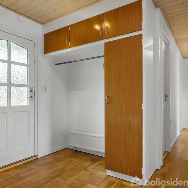 Dør i hvidt træ og glas står i en gang med trægulv og indbyggede skabe. Lange korridorer ses i baggrunden.