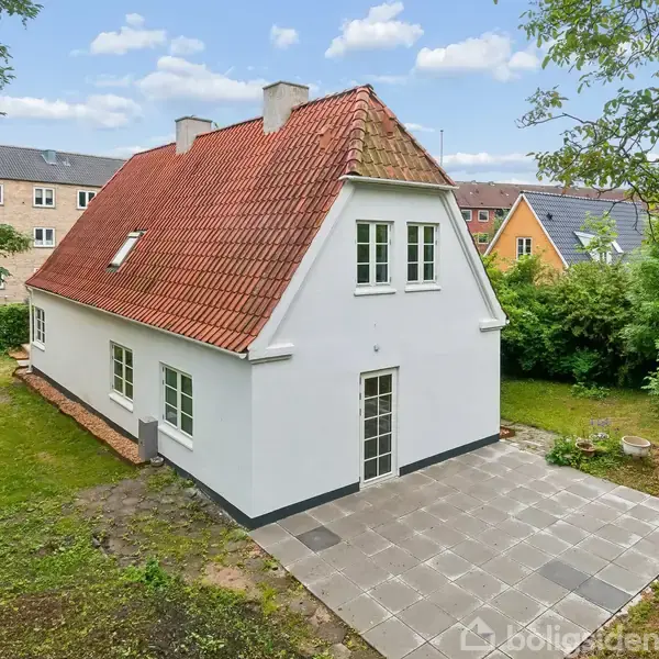 To sorte stole står ved siden af et lille bord i et lyst rum. Bordet har en dekorativ skål, og der ses et gulvlys og åbne glasdøre i baggrunden.