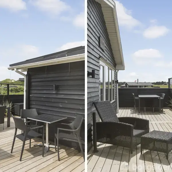 Udendørs terrasse med havemøbler af sort flet omkring et bord til venstre. Til højre er der en grill og flere siddepladser. Omgivelserne er grønt landskab under en blå himmel.