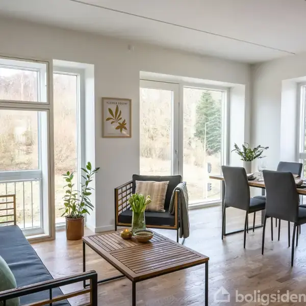En stue med en sort sofa og sofabord, ved siden af et spisebord med stole. Store vinduer viser en udsigt til træer udenfor. Planter pynter rummet.