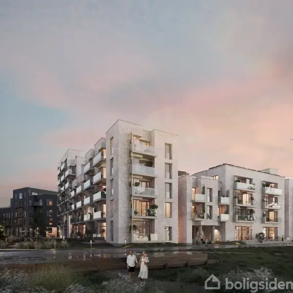 Moderne lejlighedskompleks med flade tage og store vinduer, badet i blødt aftenlys. Omgivet af grønne områder og gangbroer, med mennesker der går langs en sti i forgrunden.