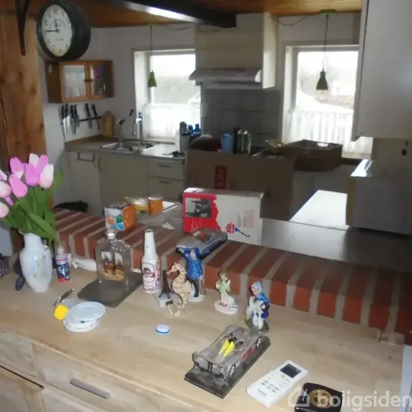 Vase med lyserøde tulipaner står på et køkkenbord i et hjem. Bordet er fyldt med forskellige genstande, og i baggrunden ses et åbent køkken med vinduer og hængende lamper.